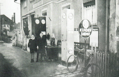 ESSO-Tankstelle „beim Ammann" (Hauptstr., alte Hausnr. 65) 1934. Die Zapfsäulen wurden 1945 von den Amerikanern zerstört. Die Buben (rechts Anton Herre) stehen am Ölfaß. Im Hintergrund auf der Treppe steht Frau Anna Ammann.