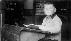 Rudolf Muninger in der Schulbank 1940. Im Hintergrund Buchstabentafel und Zählmaschine für den Erstunterricht